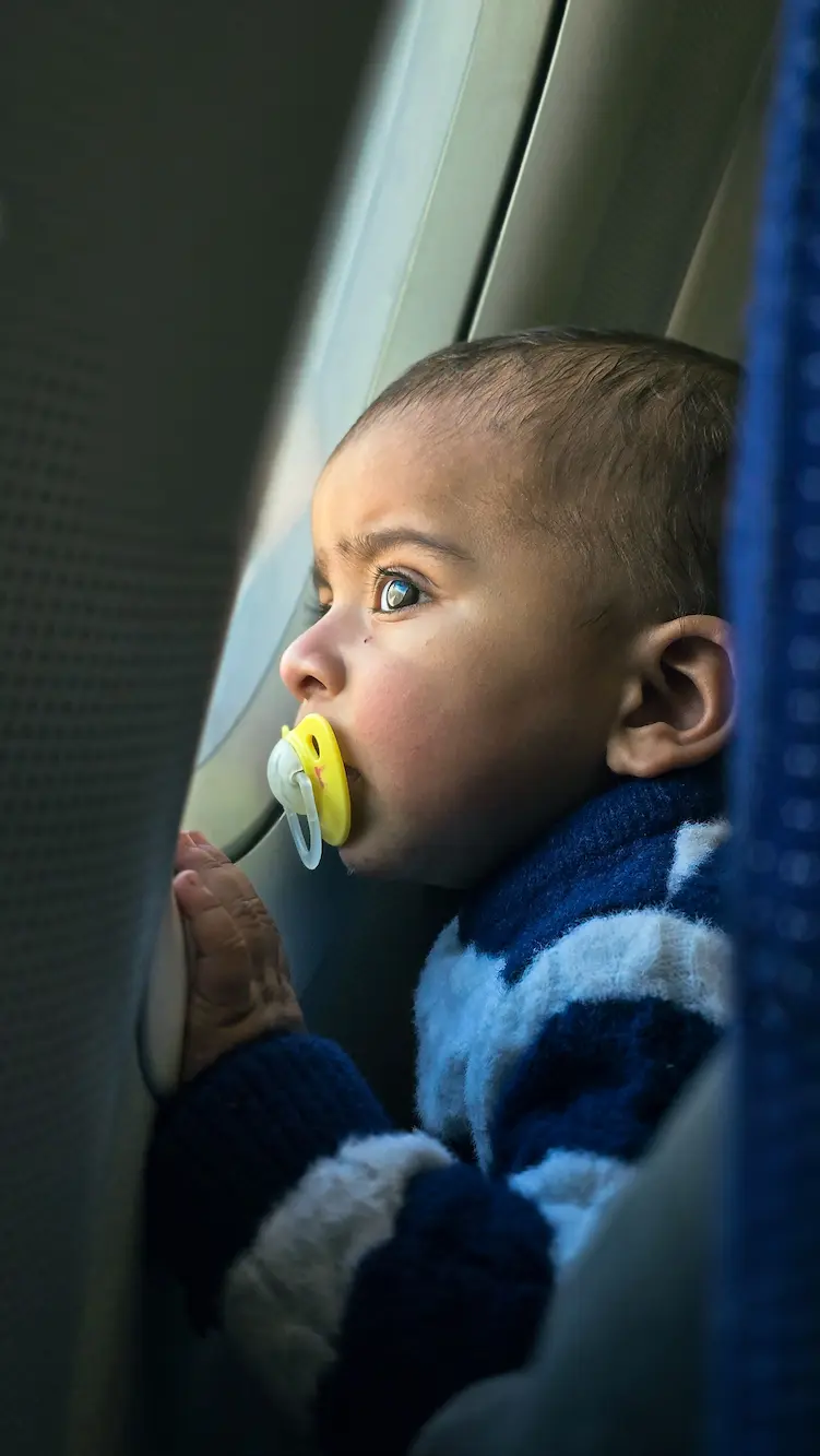 baby in a airplane looking out of the window on an international fligh